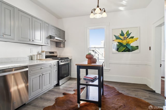 kitchen featuring stainless steel appliances, dark hardwood / wood-style floors, gray cabinets, and hanging light fixtures