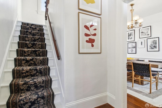 staircase with wood-type flooring and a chandelier