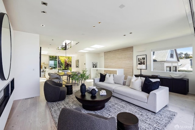 living room featuring light wood-type flooring and a skylight