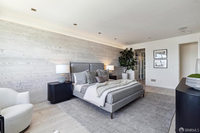 bedroom with light hardwood / wood-style flooring and wooden walls