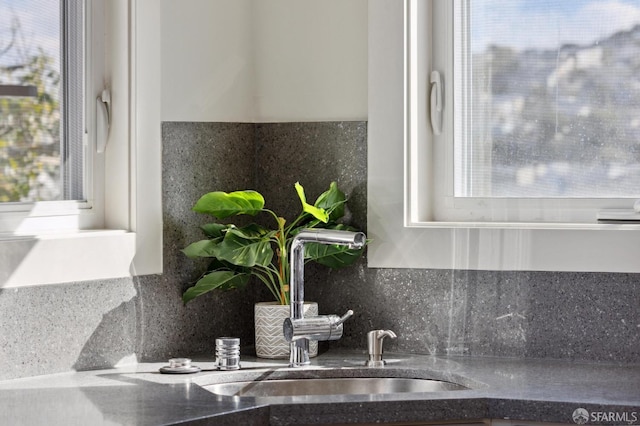 room details featuring tasteful backsplash, dark stone countertops, a sink, and indoor wet bar
