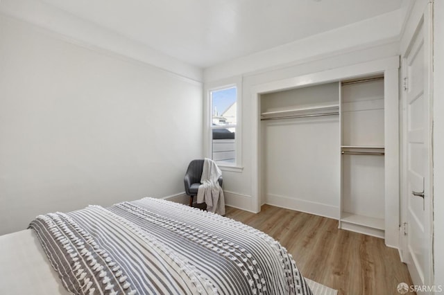 bedroom with a closet, baseboards, and wood finished floors