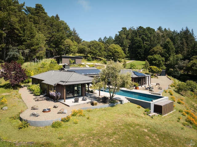 rear view of house with a lawn, a patio area, and an outdoor pool