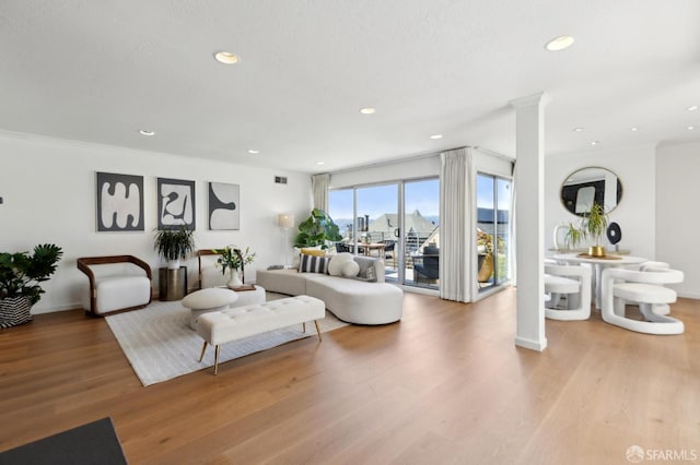 living area with wood finished floors, recessed lighting, baseboards, and ornate columns