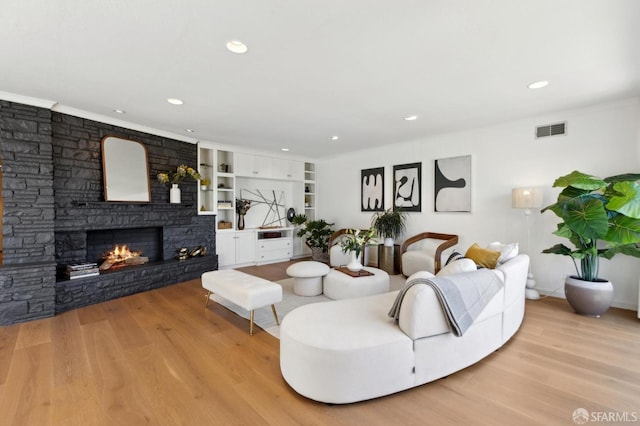 living room with a fireplace, light wood-style flooring, recessed lighting, and ornamental molding