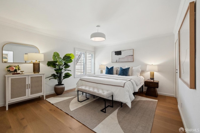 bedroom featuring crown molding, wood finished floors, and baseboards