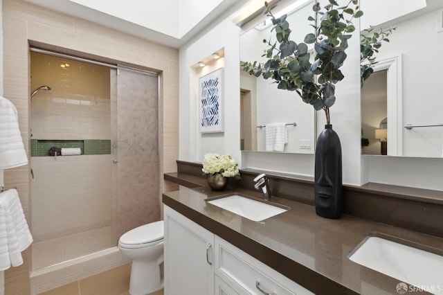 bathroom with tiled shower, toilet, and double vanity