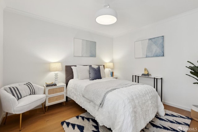 bedroom featuring ornamental molding, wood finished floors, and baseboards