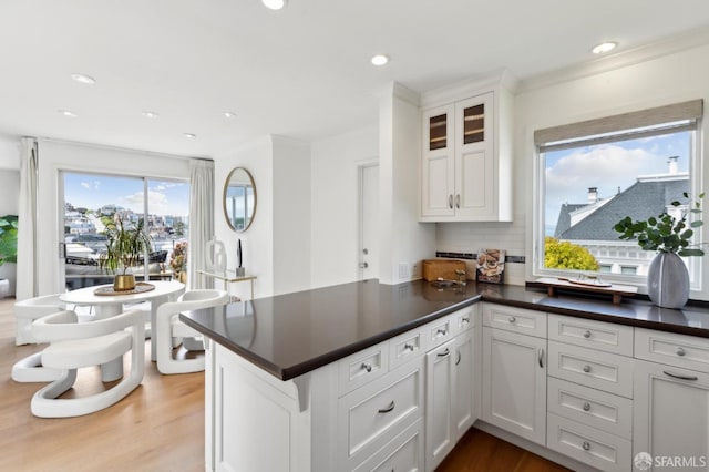 kitchen featuring a peninsula, backsplash, dark countertops, wood finished floors, and recessed lighting