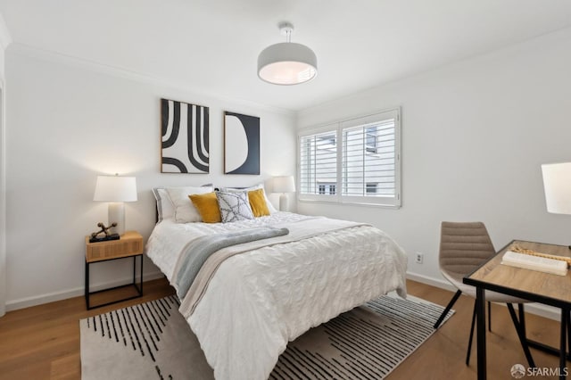 bedroom with wood finished floors, baseboards, and ornamental molding