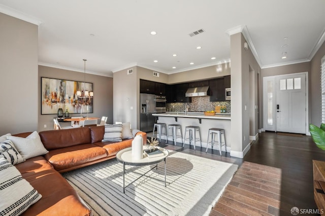 living room with ornamental molding, dark hardwood / wood-style floors, a notable chandelier, and sink