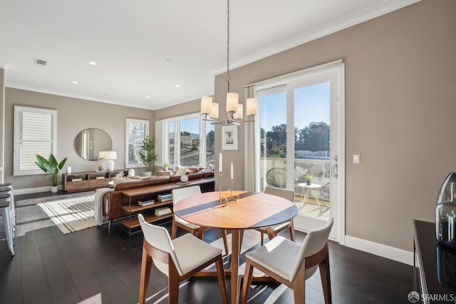 dining area with dark wood-type flooring, ornamental molding, and an inviting chandelier