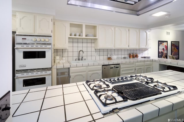 kitchen with tile counters, white appliances, and sink