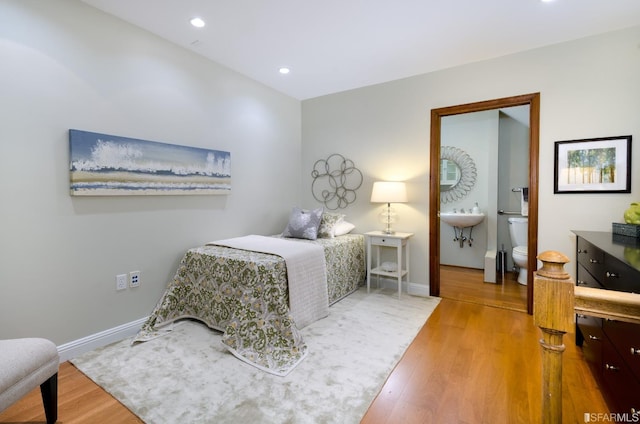 bedroom with hardwood / wood-style floors and ensuite bath