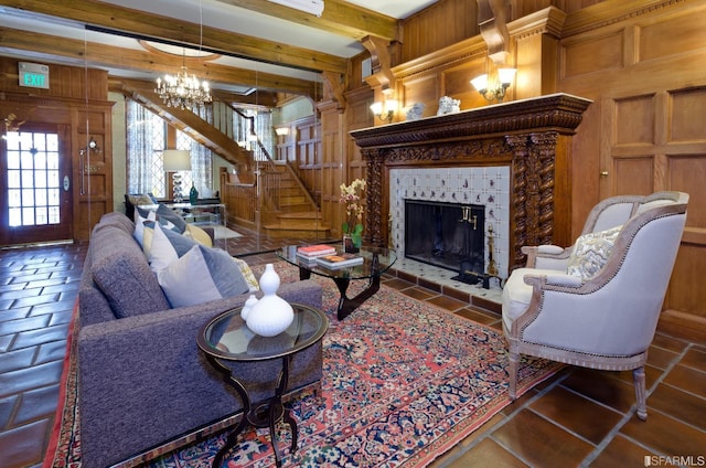 living room featuring wooden walls, a tiled fireplace, beamed ceiling, and a notable chandelier