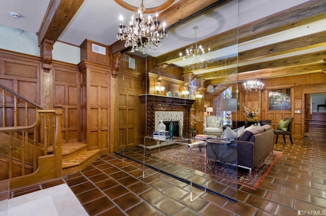 living room featuring wood walls, beamed ceiling, a chandelier, and a fireplace