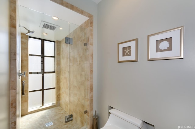 bathroom featuring a shower with door and toilet