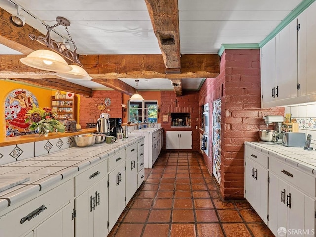 kitchen with tile countertops, brick wall, and beam ceiling