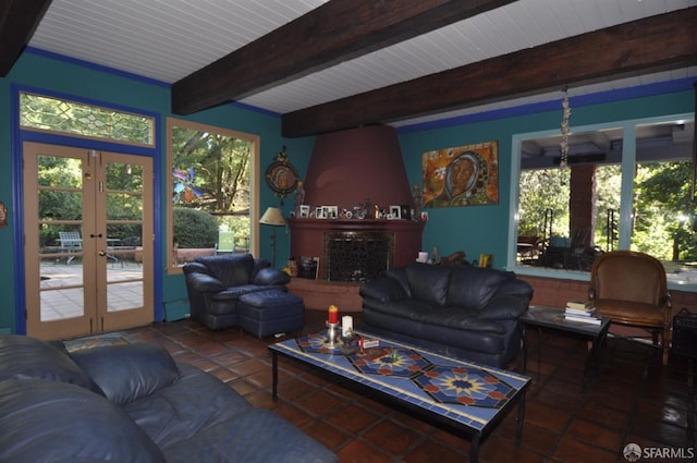 living room with a large fireplace, beam ceiling, and french doors