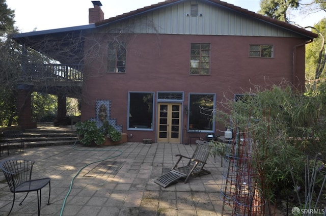 back of house featuring a patio, a chimney, a tiled roof, french doors, and stucco siding