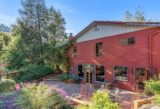 back of house with a patio, a chimney, and stucco siding