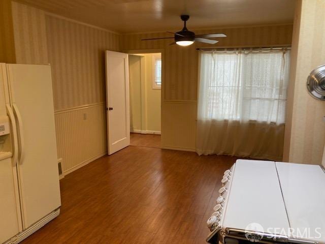 interior space with dark wood-type flooring, ceiling fan, and white fridge with ice dispenser