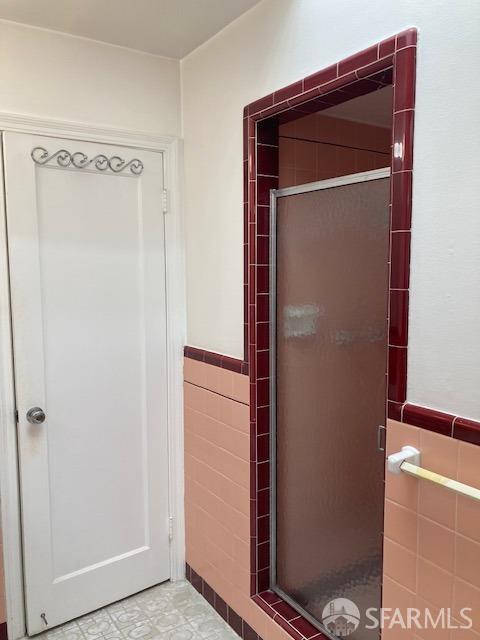 bathroom with tile walls and a shower with shower door