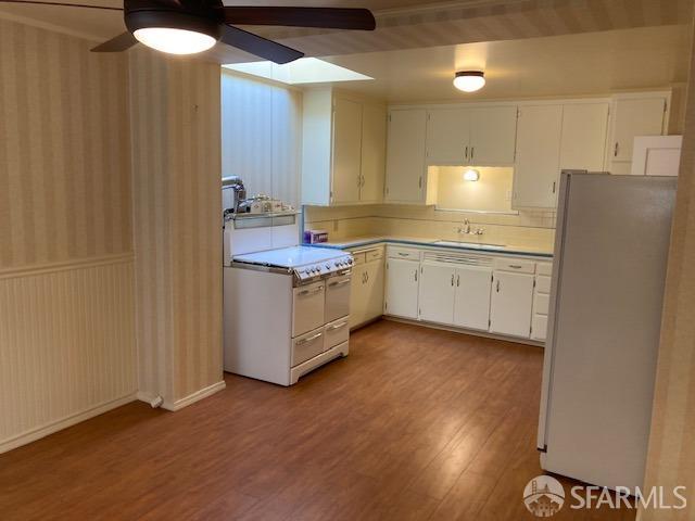 kitchen featuring ceiling fan, white cabinets, refrigerator, and sink