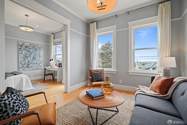 living area with crown molding, baseboards, and light wood-type flooring