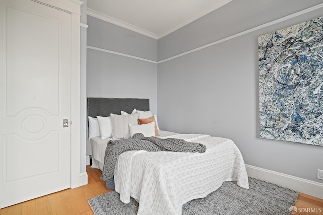 bedroom with wood finished floors, ornamental molding, and baseboards