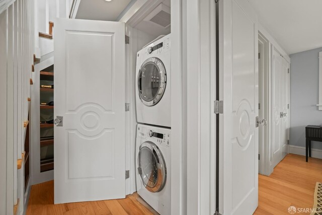 laundry room featuring stacked washer and dryer, light wood-style floors, and laundry area
