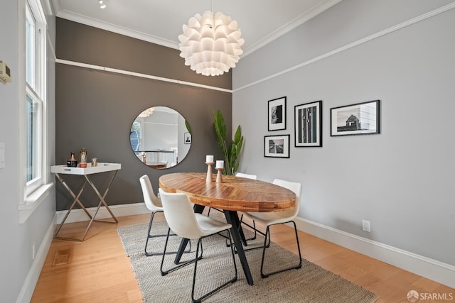 dining space featuring baseboards, wood finished floors, and crown molding
