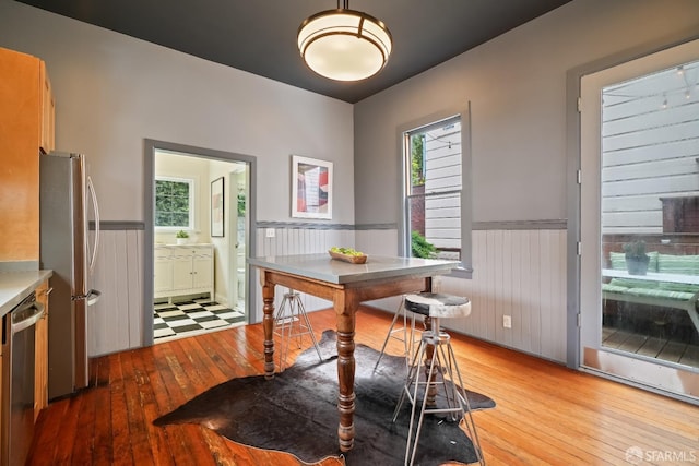dining room featuring light wood-type flooring and a wainscoted wall