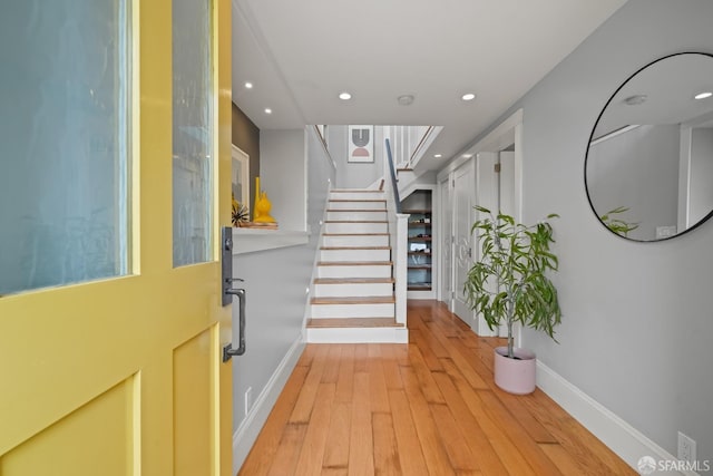 entryway featuring wood-type flooring, recessed lighting, stairs, and baseboards