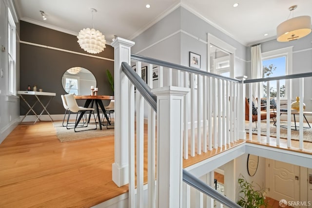 stairway featuring recessed lighting, wood finished floors, an inviting chandelier, and crown molding