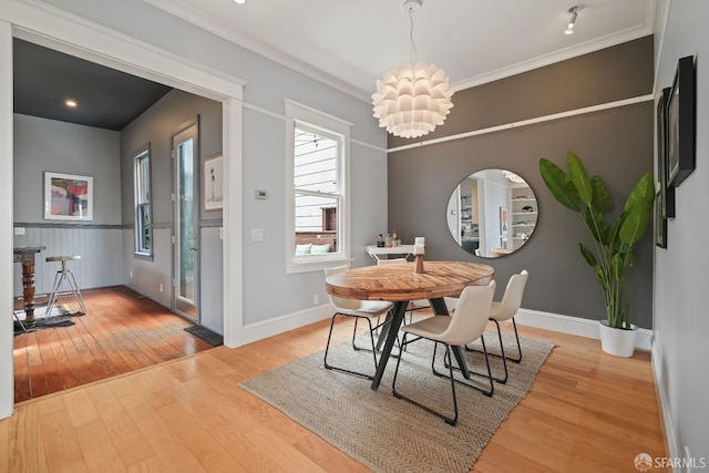 dining room featuring baseboards, light wood-type flooring, ornamental molding, and an inviting chandelier