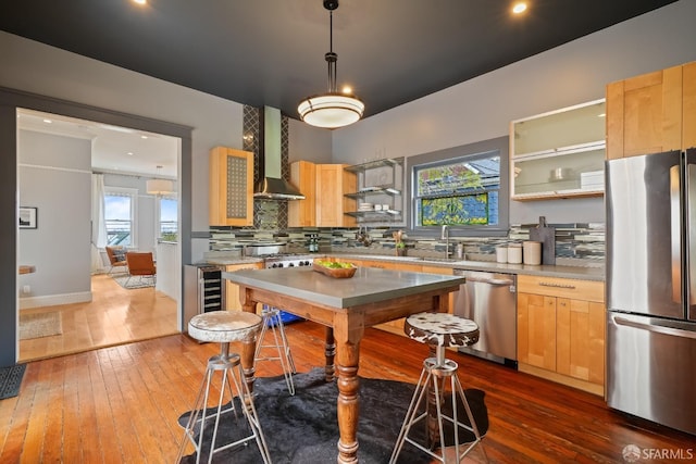 kitchen featuring wall chimney exhaust hood, backsplash, appliances with stainless steel finishes, and light brown cabinets