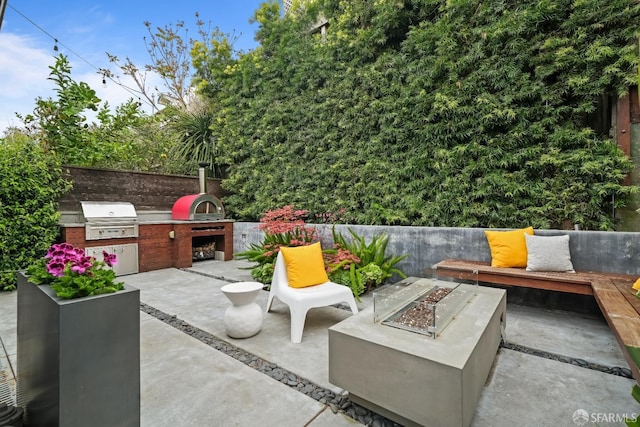 view of patio / terrace featuring a fire pit, fence, area for grilling, and exterior kitchen