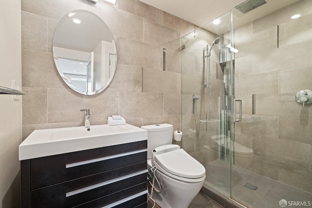 full bathroom with vanity, toilet, a stall shower, and tile walls