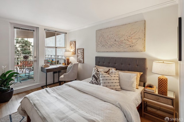 bedroom featuring hardwood / wood-style flooring, access to exterior, and crown molding