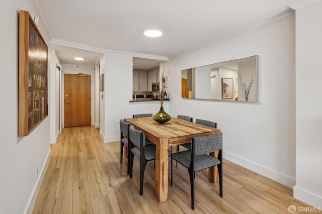 dining area featuring ornamental molding and light hardwood / wood-style flooring