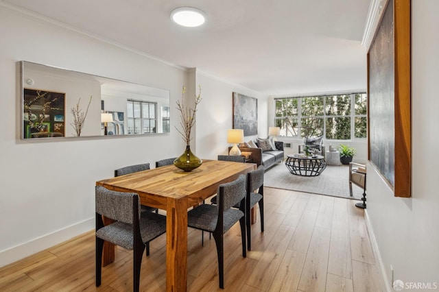 dining space with ornamental molding, a healthy amount of sunlight, and light hardwood / wood-style flooring