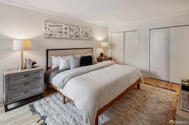 bedroom with hardwood / wood-style flooring, crown molding, and two closets