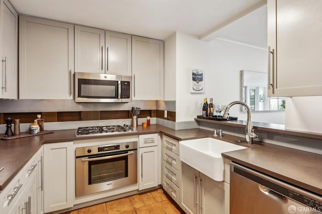 kitchen with sink, light tile patterned floors, stainless steel appliances, and white cabinets