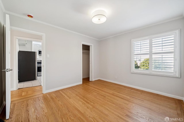 unfurnished bedroom with light wood finished floors, baseboards, crown molding, and freestanding refrigerator