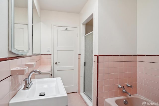 bathroom with tile walls, a bathing tub, wainscoting, a sink, and walk in shower