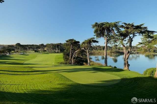 view of community featuring view of golf course, a water view, and a yard