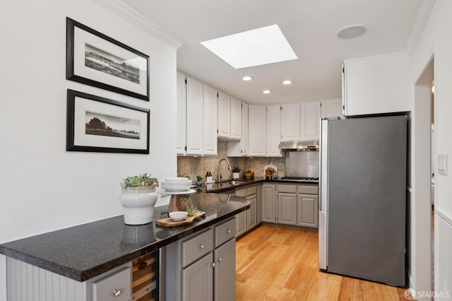 46 Otsego Ave, San Francisco, CA 94112 - kitchen featuring freestanding refrigerator, a skylight, light wood-type flooring, tasteful backsplash, and under cabinet range hood