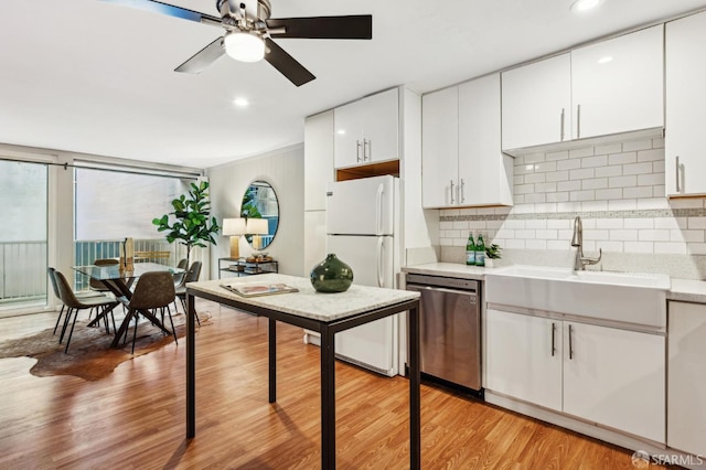 kitchen with light wood-style flooring, a sink, light countertops, stainless steel dishwasher, and tasteful backsplash