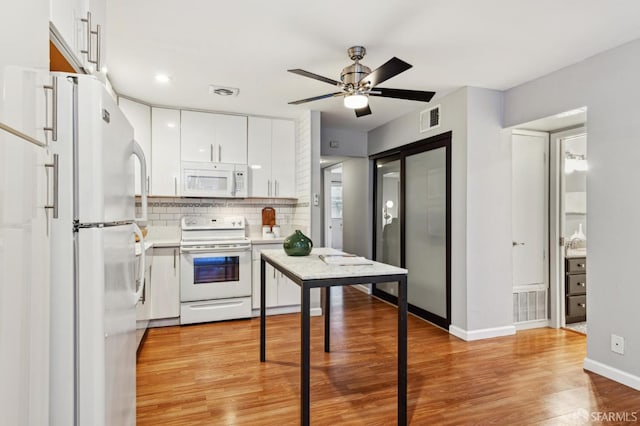 kitchen with light wood-type flooring, white appliances, visible vents, and white cabinets